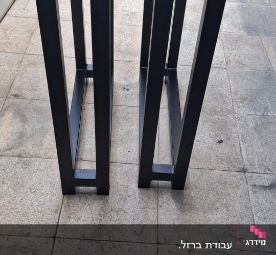 שני מסגרות מתכת שחורות על רצפת בטון
